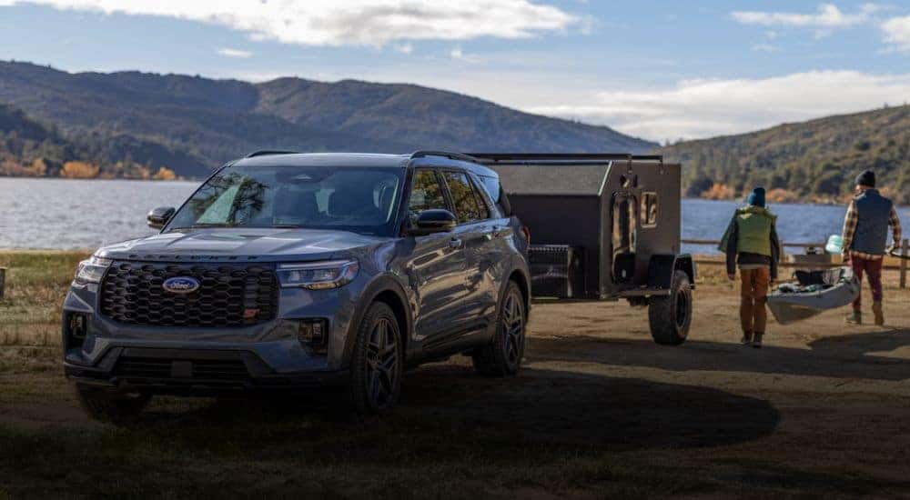 A blue 2026 Ford Explorer parked in front of a lake with a trailer attached.