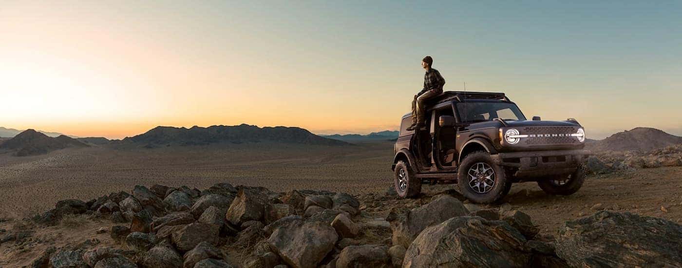 Black 2021 Ford Bronco in the Badlands with a a man sitting on the roof.