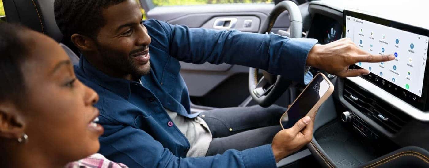 Two people using the infotainment screen in a 2026 Ford Explorer.