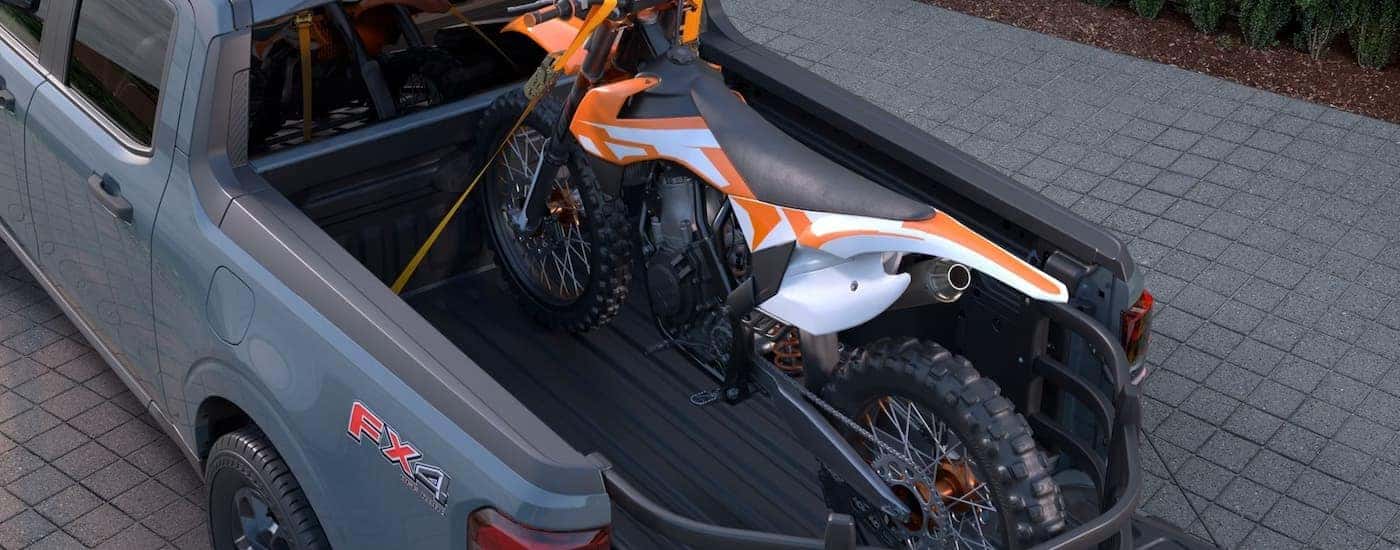 Dirt bike in the bed of a gray 2026 Ford Maverick.