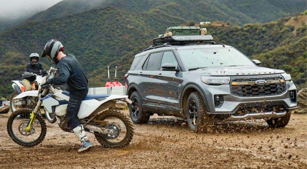 A gray 2026 Ford Explorer parked by people dirtbiking.