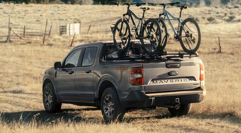 A gray 2026 Ford Maverick Tremor parked in a field with two bikes mounted.