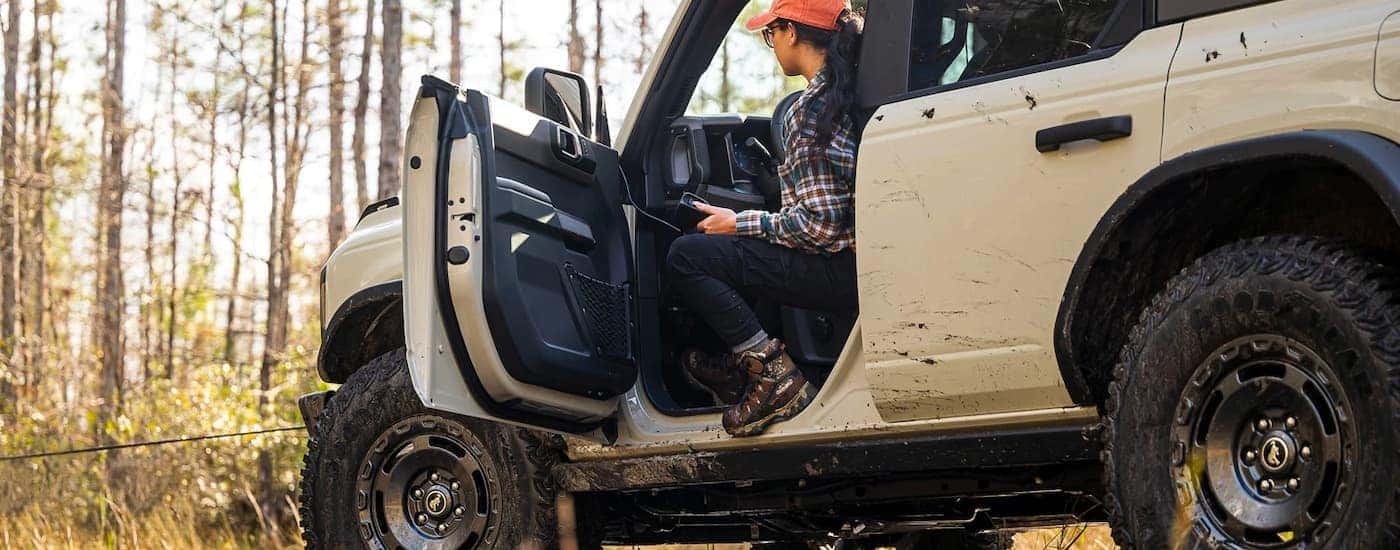 A person sitting in the driver seat of a white 2022 Ford Bronco Sport
