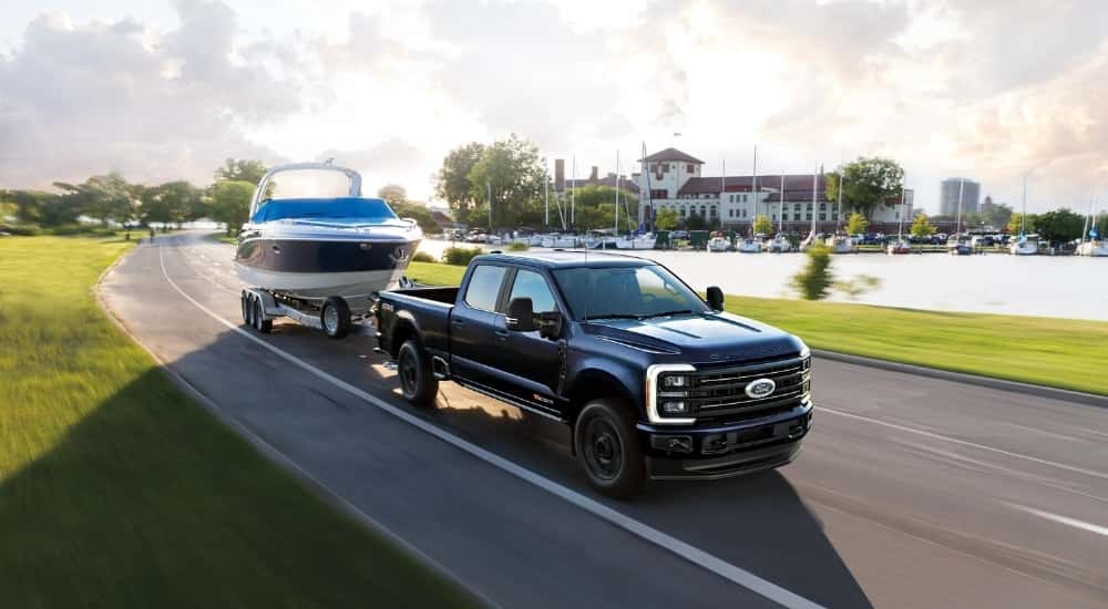 Black 2026 Ford F-350 towing a boat around a bend.