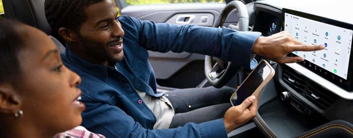 Two people using the infotainment screen in a 2026 Ford Explorer.