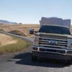 Brown 2026 Ford F-350 Lariat towing a trailer down a road.