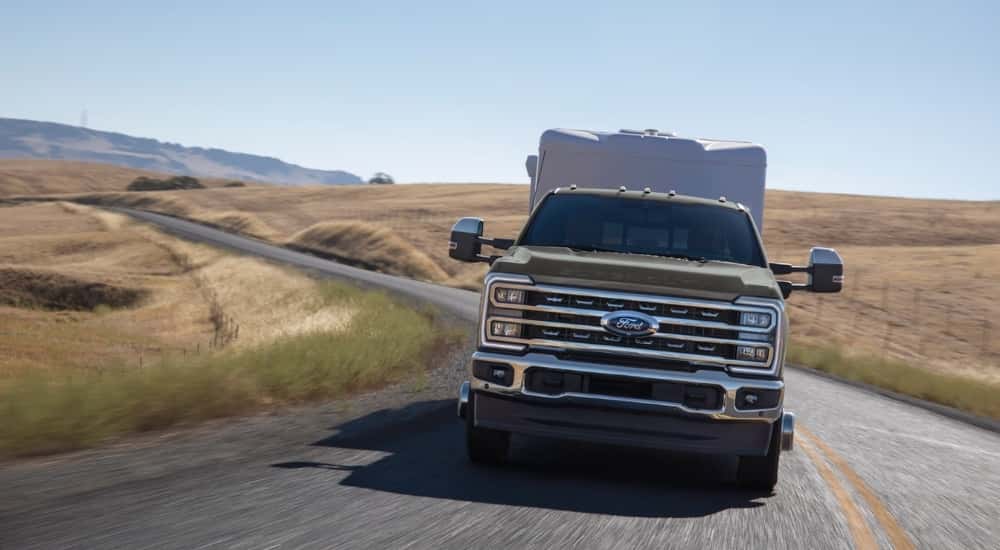Brown 2026 Ford F-350 Lariat towing a trailer down a road.