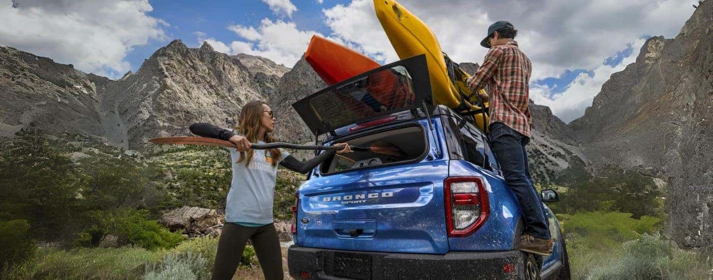 A blue 2022 Ford Bronco Sport being loaded with kayaks.