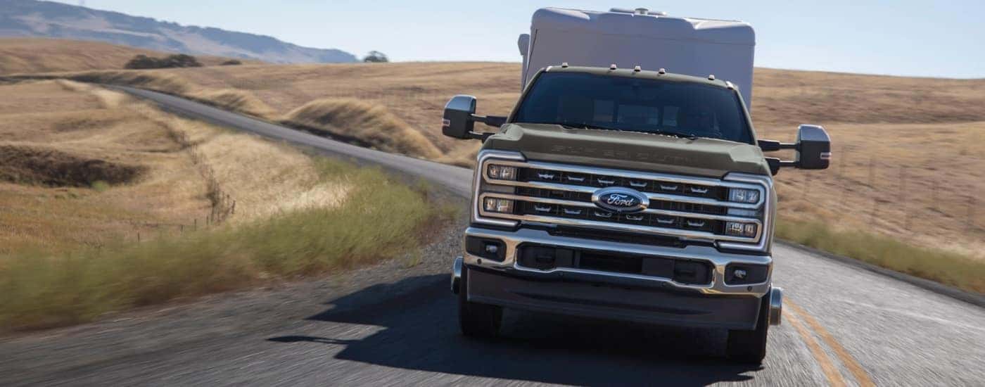A gray 2026 Ford F-350 Lariat showing driving head-on with a trailer.