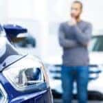 A man thinking about a decision on a car.