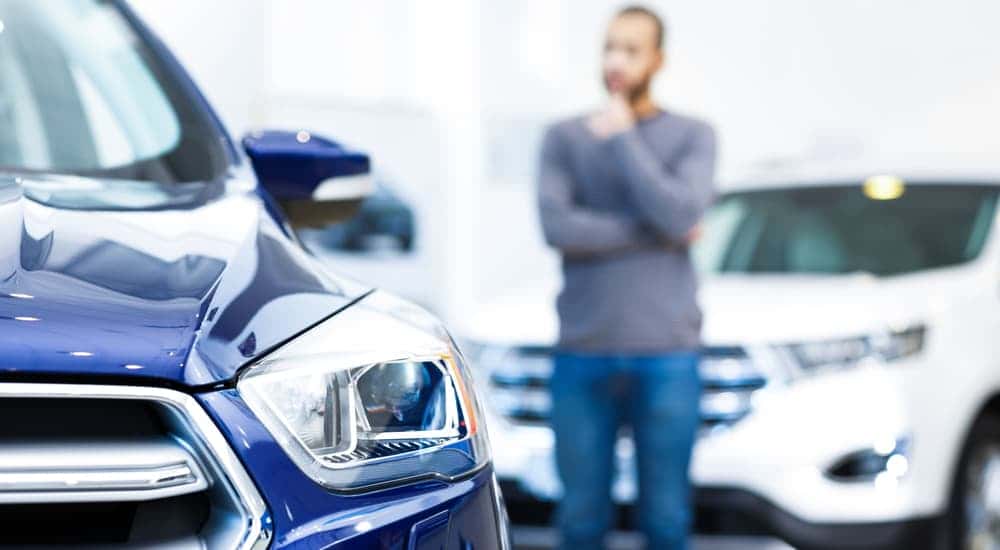 A man thinking about a decision on a car.