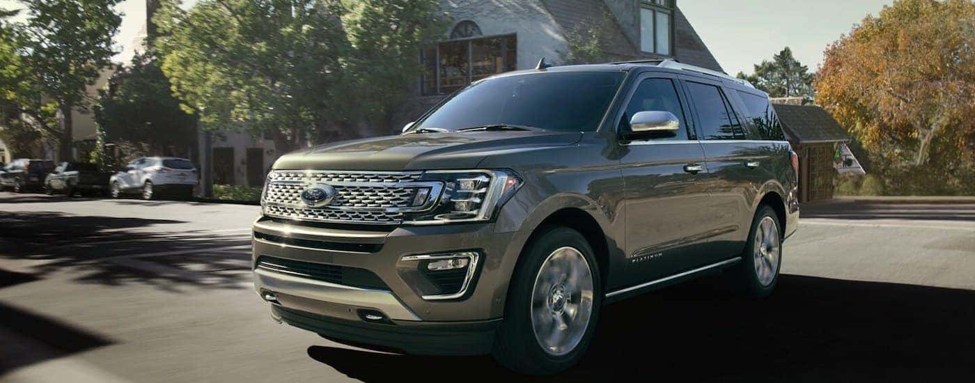 Gold 2020 Ford Expedition Platinum driving on a paved road.