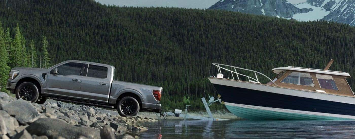 Grey 2026 Ford F-150 Lariat towing a boat out of a body of water.