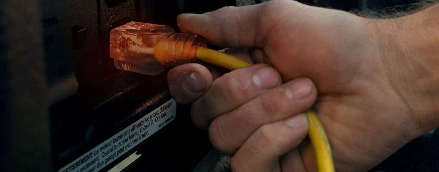A person plugging a cord into the Pro Power Onboard on a 2026 Ford F-150 XLT.