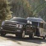 A black 2026 Ford F-150 Lariat towing a trailer.