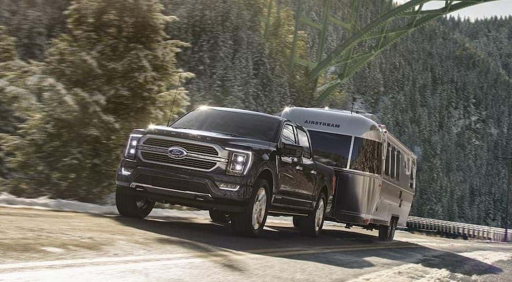 A black 2026 Ford F-150 Lariat towing a trailer.