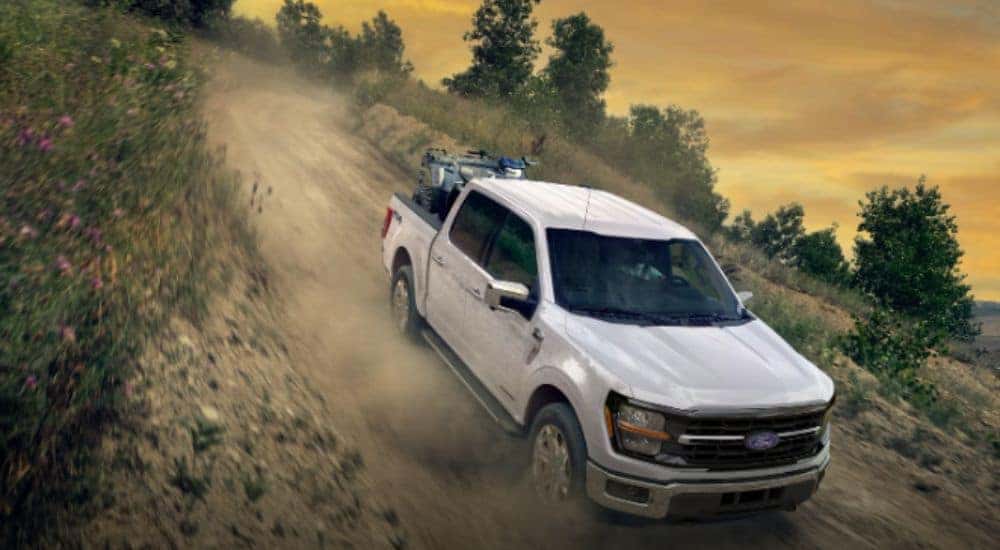 White 2026 Ford F-150 driving off-road downhill.