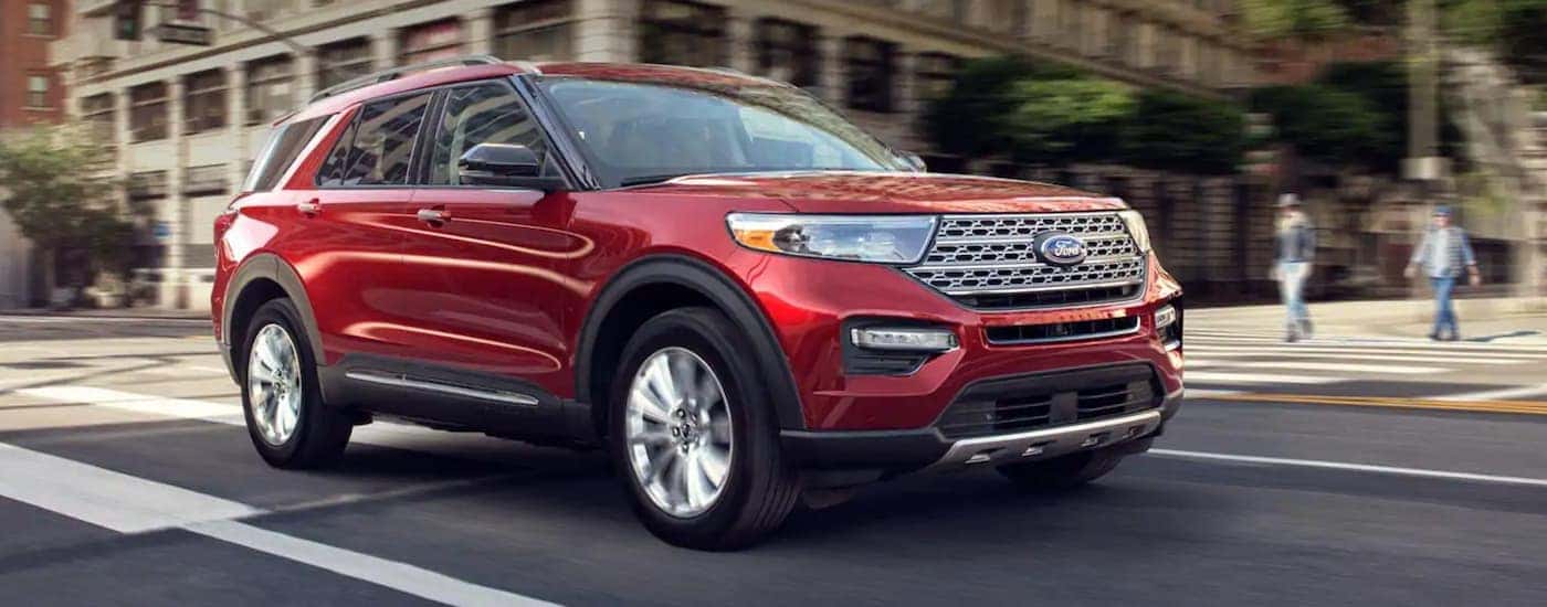 A red 2020 Ford Explorer driving in a city.