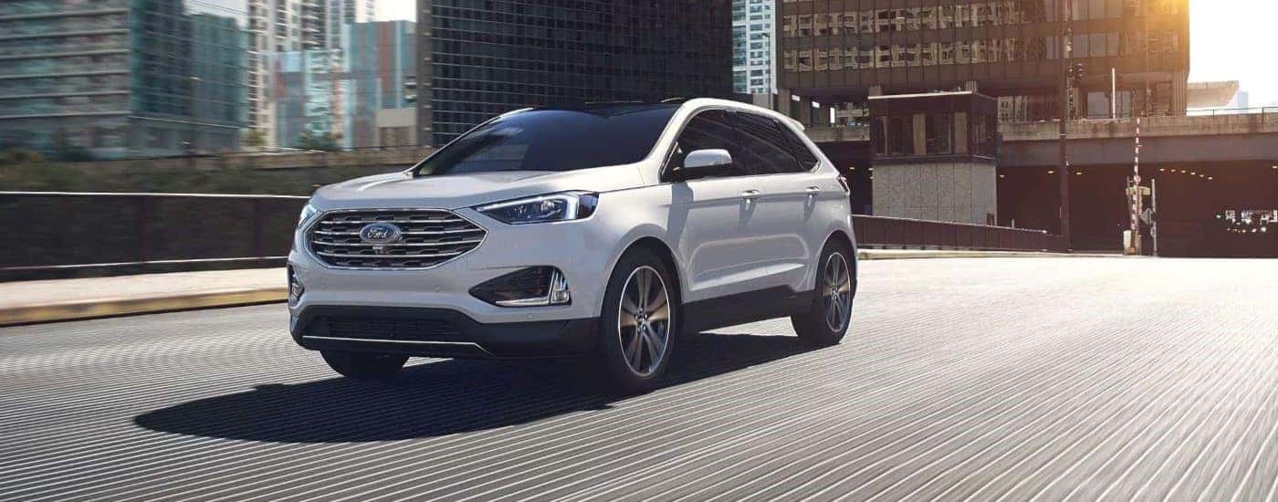 A white 2024 Ford Edge driving in a city.
