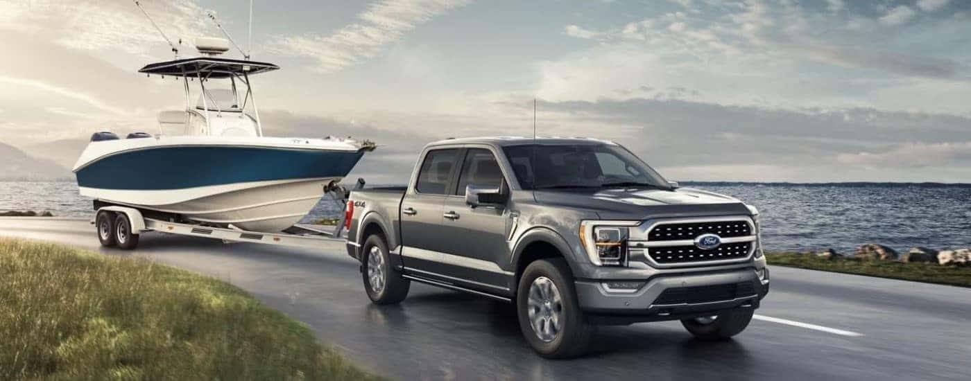 Grey 2022 Ford F-150 Limited towing a boat along the water.