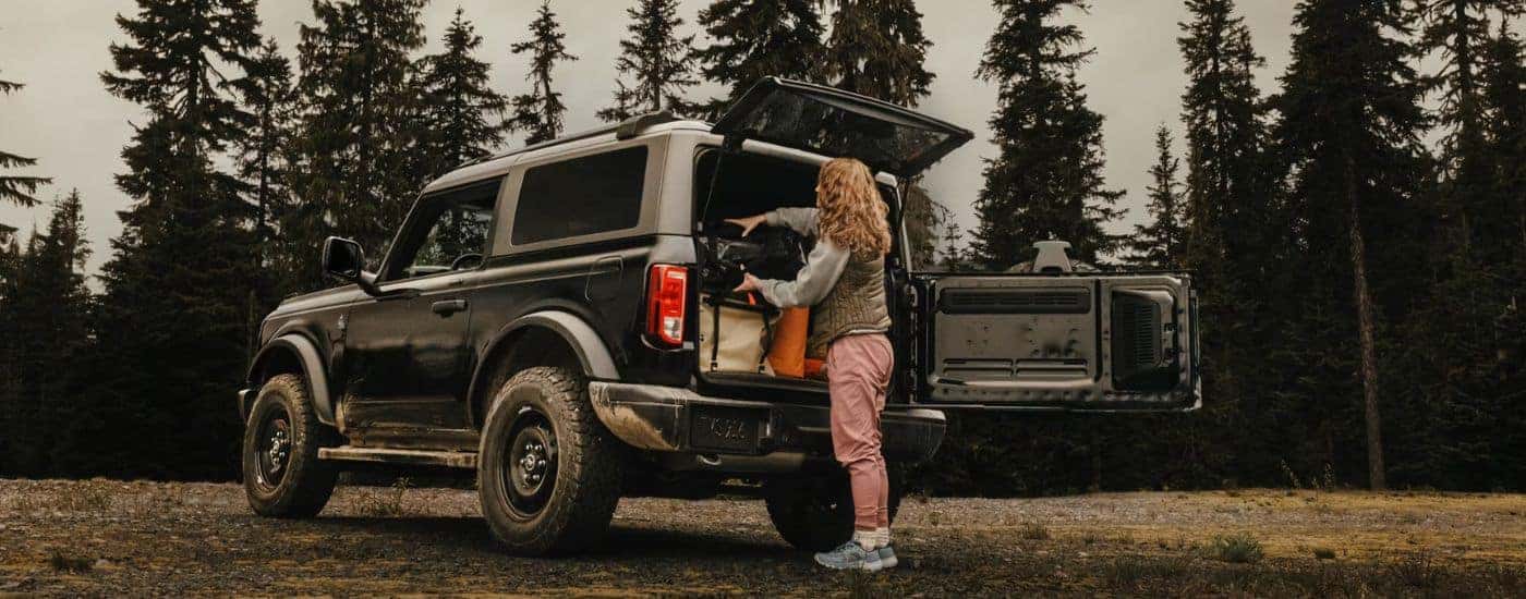 Black 2026 Ford Bronco with a woman loading the cargo area.