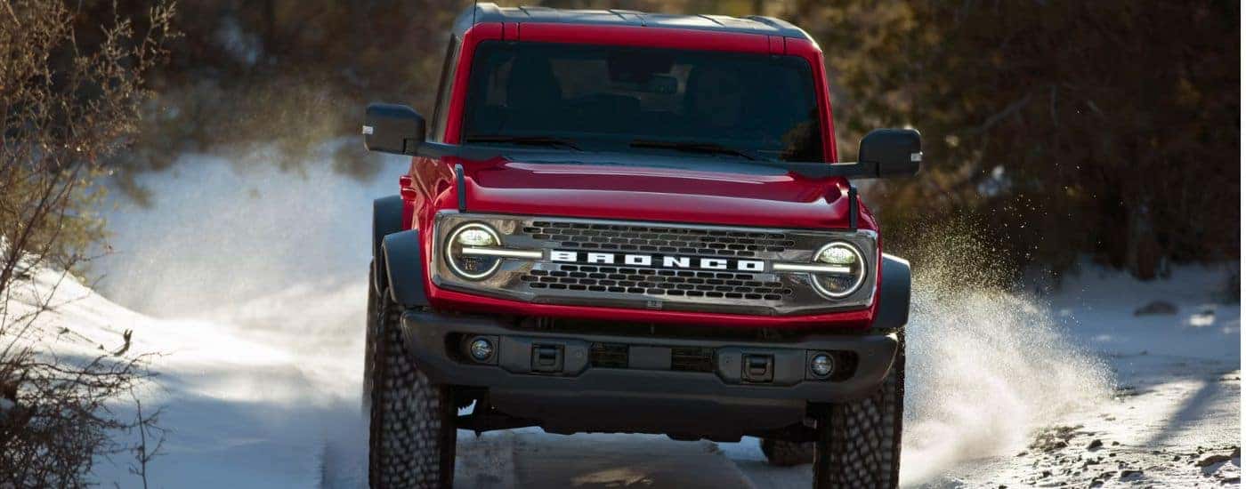 Red 2026 Ford Bronco driving through the snow.