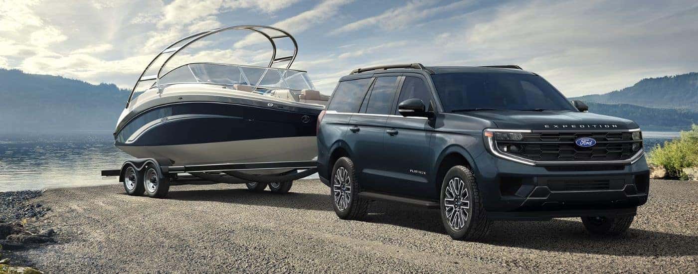 Blue 2027 Ford Expedition Platinum towing a boat.