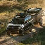 A black 2027 Ford Expedition towing a trailer on a dirt road.