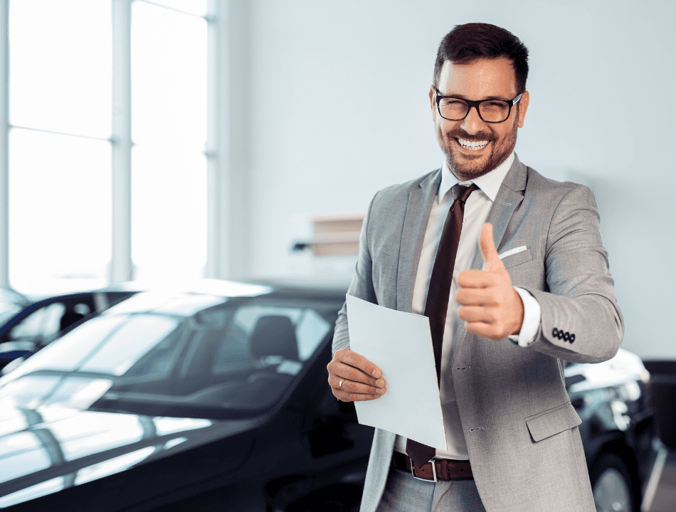 Man with glasses at Dealership with a thumbs up