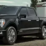 Black-Ford-F-150-towing-a-horse-trailer-on-a-paved-road-with-trees-in-the-background
