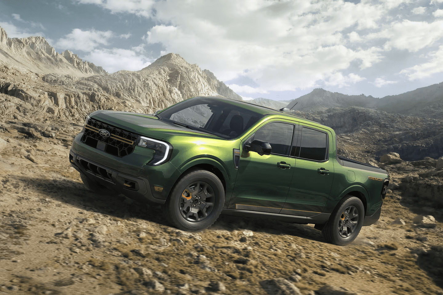 2025 Ford Maverick Tremor in green climbing a rugged mountain trail, showcasing its off-road capability and bold styling.