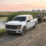 2025 Ford F-150 white pickup truck towing a small boat