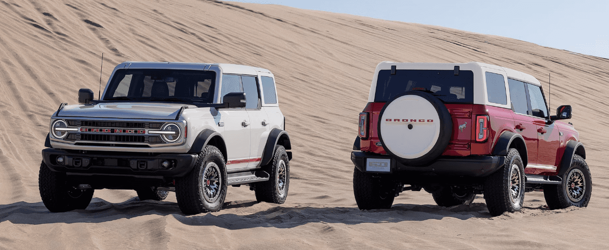 Two 2026 Ford Broncos parked side by side facing the opposite ways on the sand.