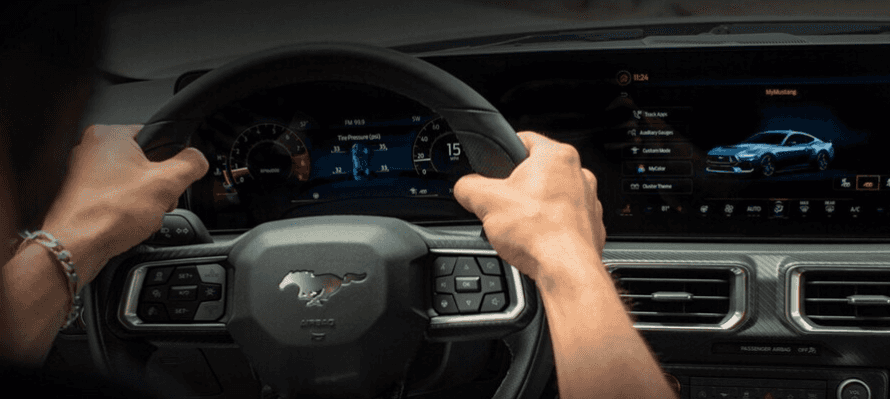 2026 Ford Mustang interior view with driver hands on steering wheel and digital instrument cluster infotainment screen