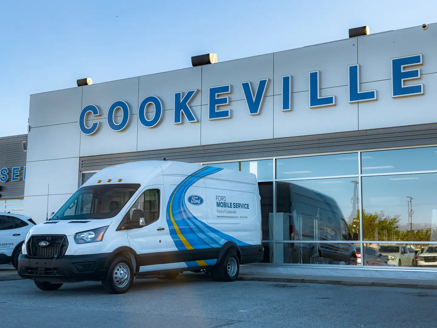 Ford Mobile Service van parked outside the Ford of Cookeville dealership building on a sunny day, with a large “Cookeville” sign above the entrance.