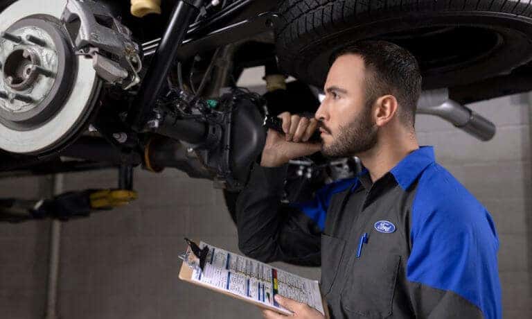 Ford Service technician inspecting under vehicle