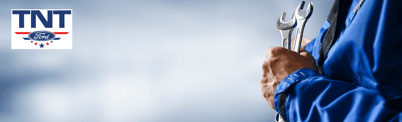 A Ford mechanic installing an OEM part on an F-150 at TNT Ford in Red Oak, IA.