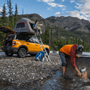 Yellow Bronco with roof top tent on a creek