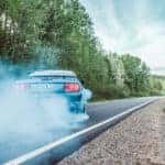 car blowing smoke while driving on the road in daylight