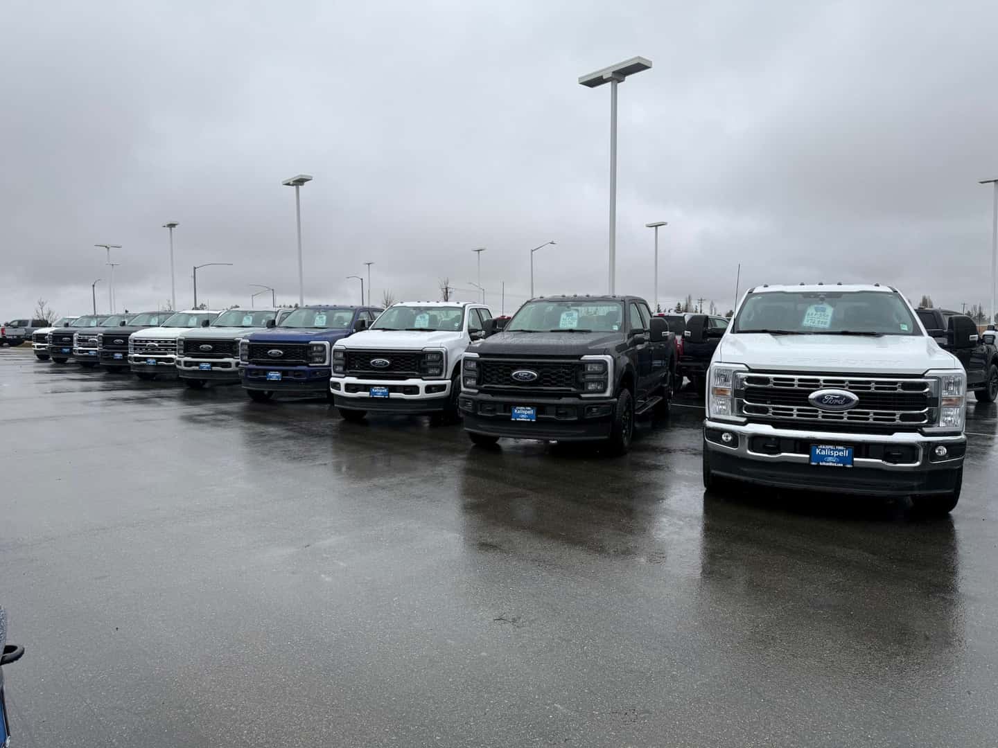Row of 2026 Ford F-350s on the Kalispell Ford lot during a rainy day