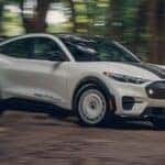2026 Ford Mustang Mach-E driving down a dirt road in a forest