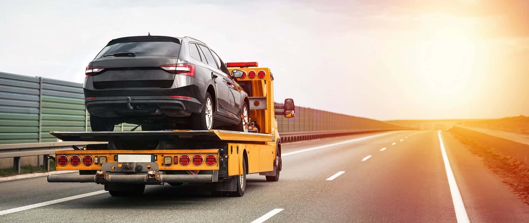 Reliable Towing and Recovery Services: 24/7 Assistance for Vehicle Breakdowns and Accidents. Emergency roadside assistance on the highway. side view of the flatbed tow truck with a damaged vehicle