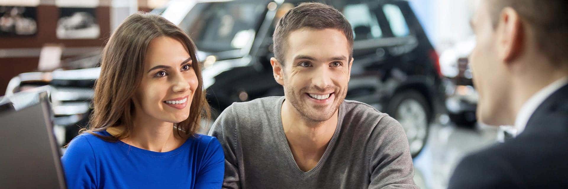 Salesman explaining all the car features to the young owners