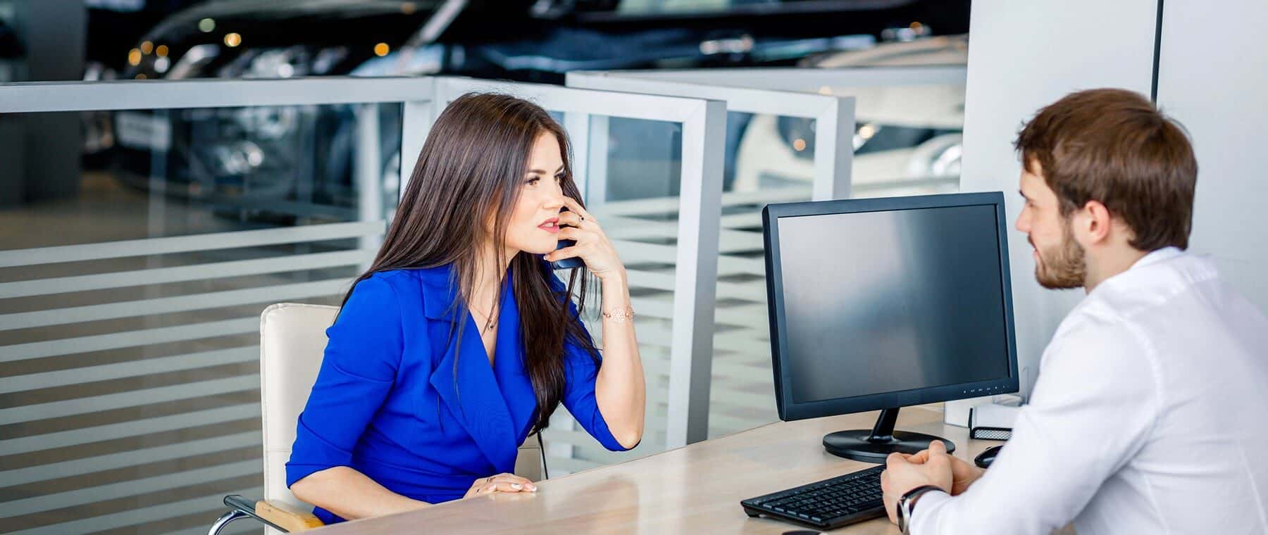 Young salesman telling customer features of of new car