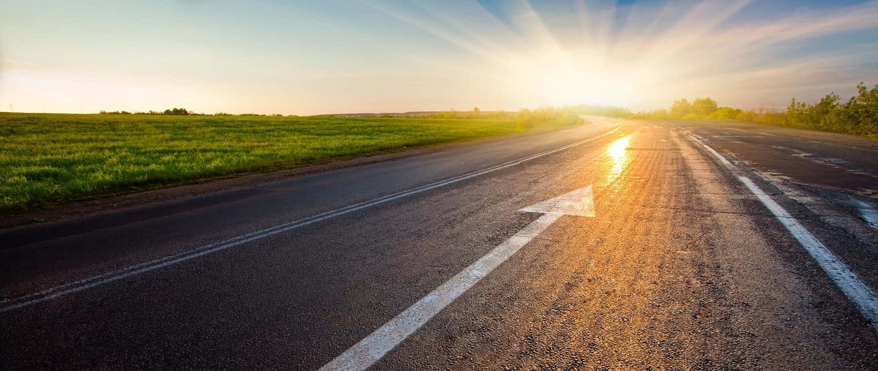 black road with arrow and a sunset