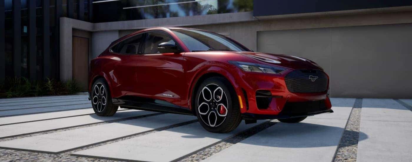 A red 2024 Ford Mustang Mach-E parked near a house.