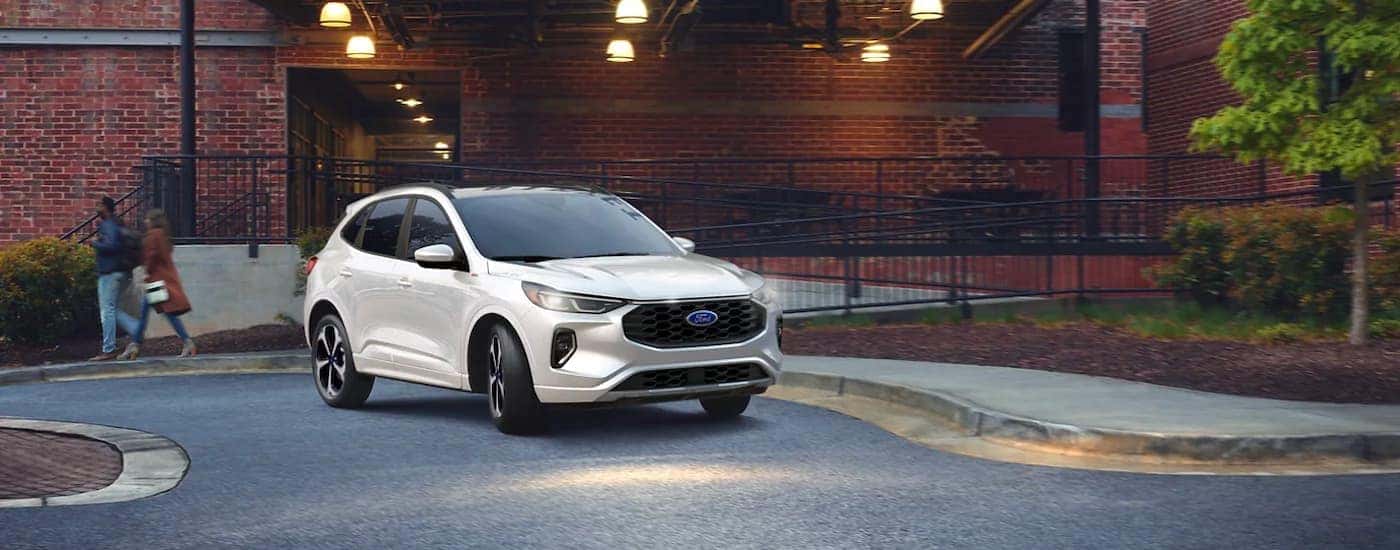 A white 2023 Ford Escape ST-Line parked outside a building.