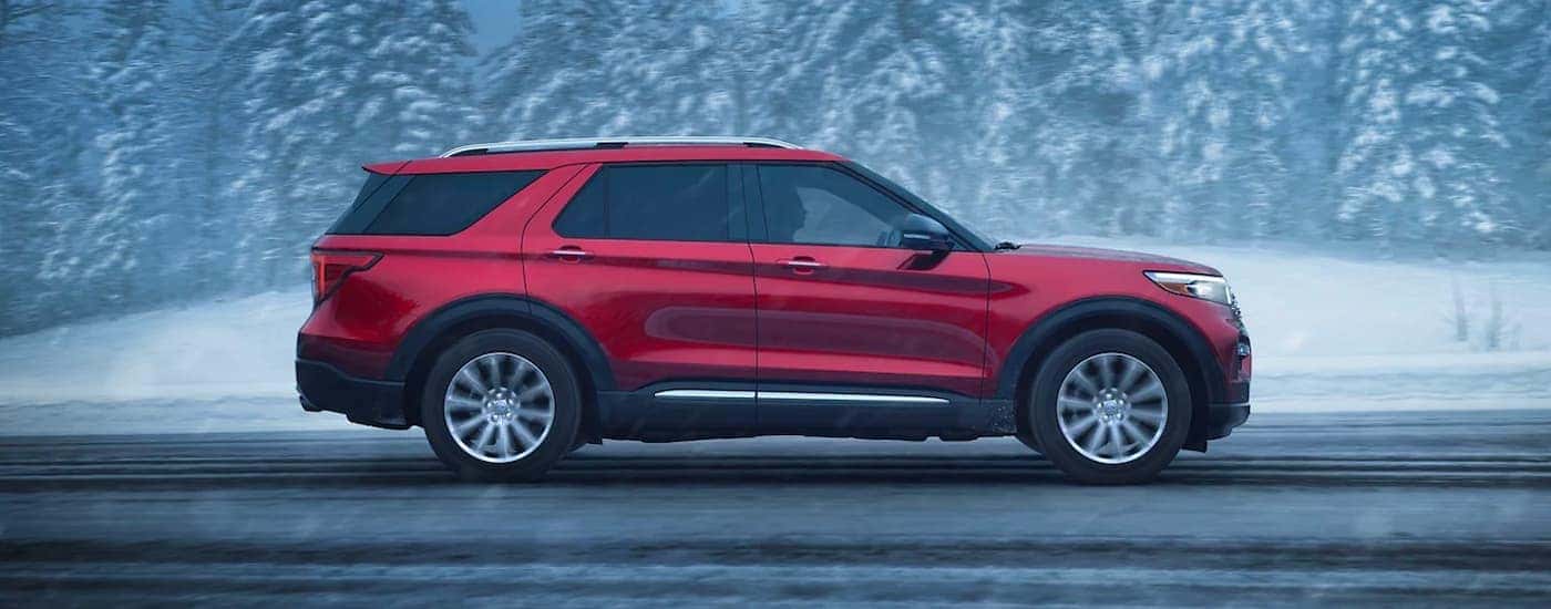 A red 2023 Ford Explorer Limited driving down a snowy road.