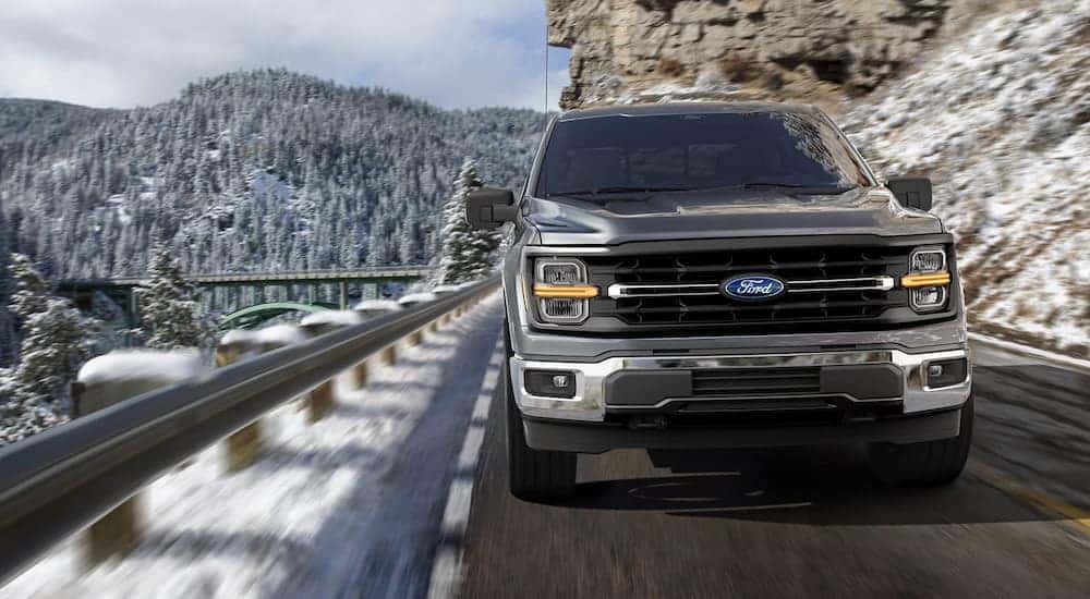A grey 2025 Ford F-150 for sale driving on a mountain road.