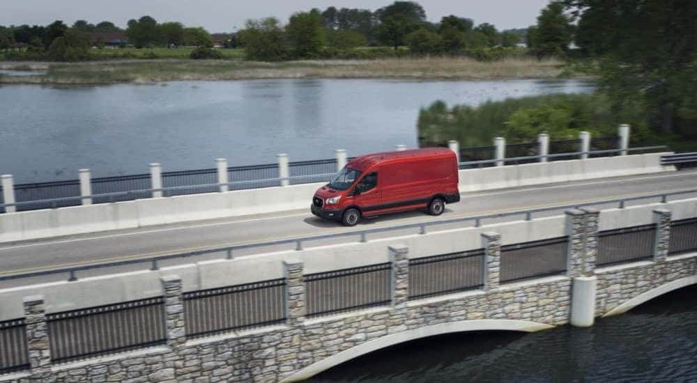 Overhead view of a red 2024 Ford Transit for sale driving over a bridge.